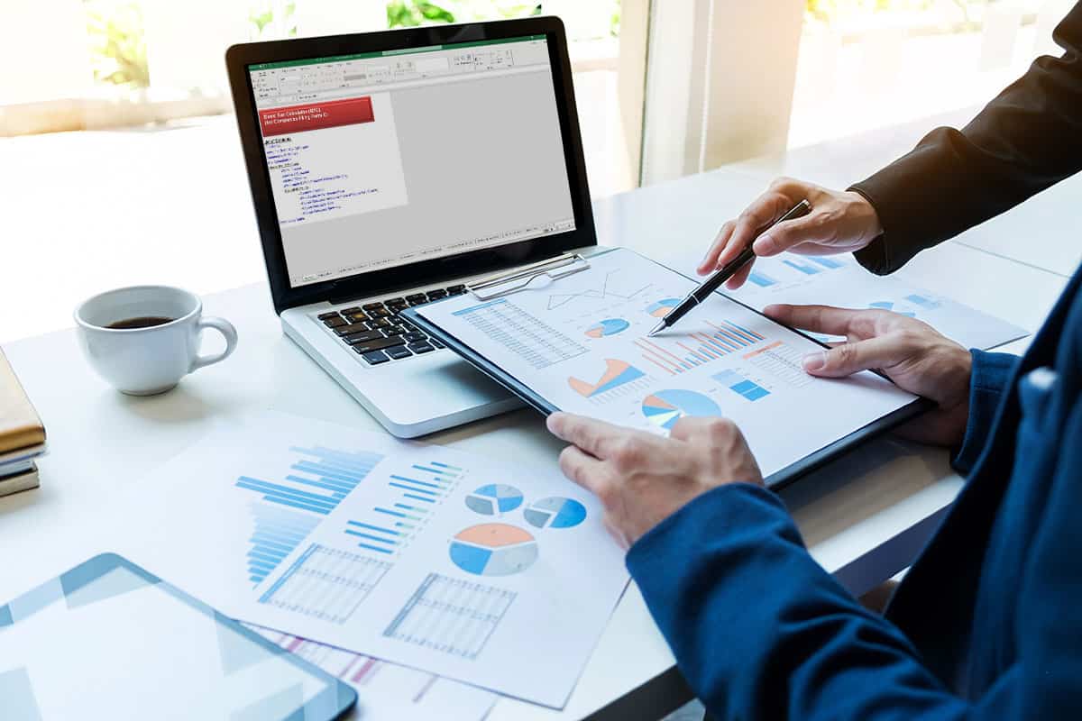 accountants discussing tax figures, various documents on office desk and a laptop showing onscreen IRAS tax calculator worksheet