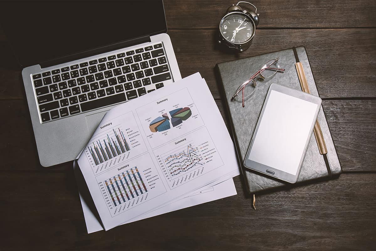 items for auditing work on a desk including laptop, glasses, notebook and an audit report