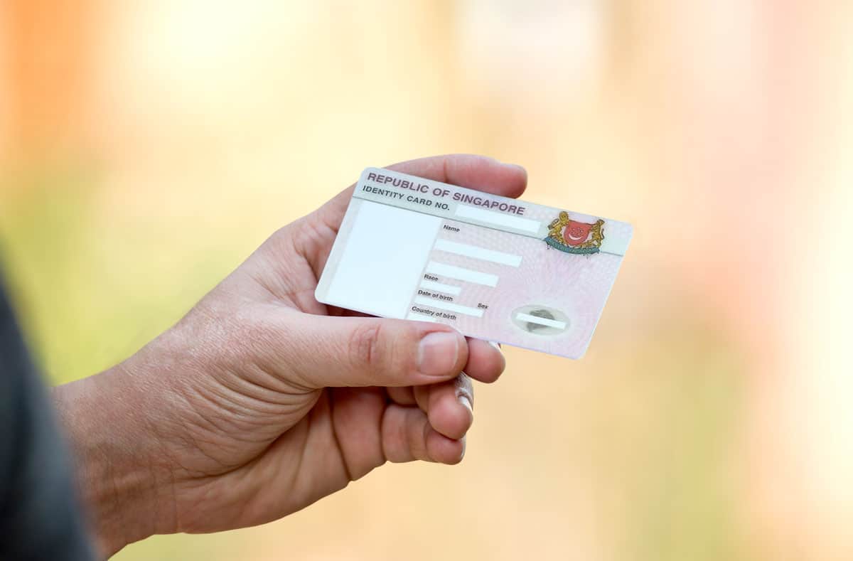 man's hand holding an NRIC which serves as a valid Singapore tax identification number