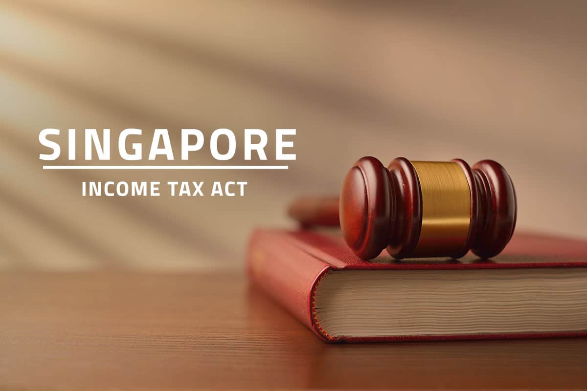 words Singapore income tax act over background of a table with a judge's gavel lying on top of a law book
